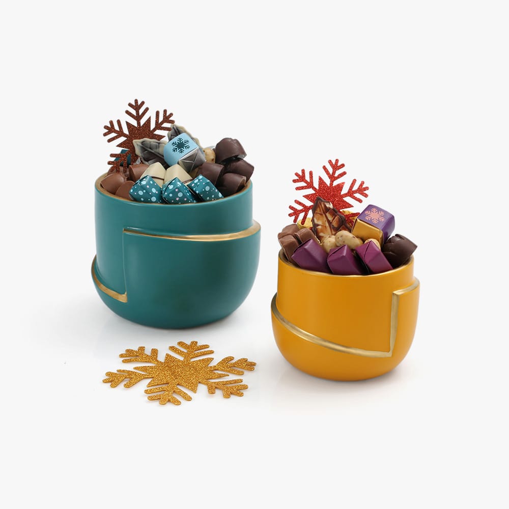 Siena Contraste saisissant entre l'orange vibrant de la coupe et les couleurs gourmandes des chocolats. Un design moderne et épuré, souligné par un anneau doré, qui en fait un objet décoratif à part entière. Poids en chocolat : <strong>200g</strong> 2 Siena – Image 2