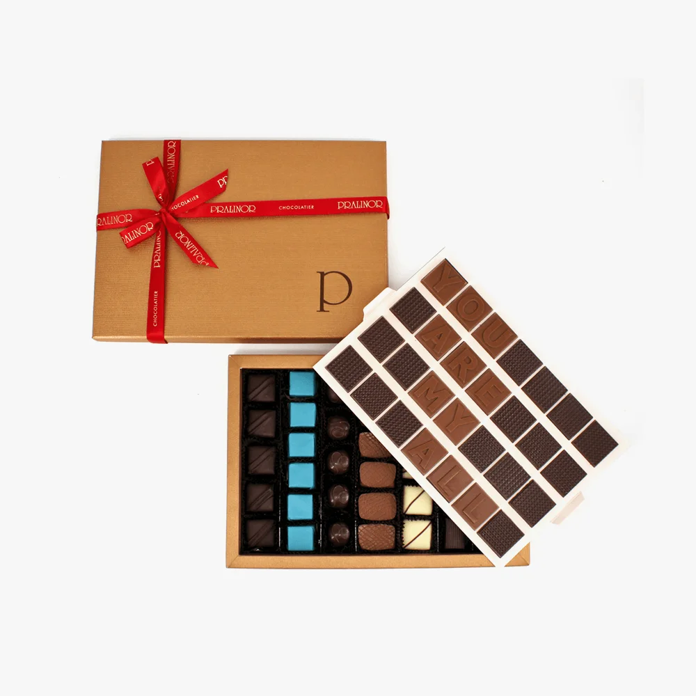 You Are My All Notre toute dernière création, un coffret Prestige Massimo Composée de deux niveaux, le premier niveau offre une sélection exquise de sept rangées de saveurs. Tandis que le niveau supérieur réserve une surprise spéciale avec un message personnalisé, quatre lignes de sept caractères chacune, pour ajouter une touche personnelle à chaque dégustation. Au total,<strong> 680g</strong> de plaisir chocolaté vous attendent dans cette boîte originale et gourmande. <strong>IMPORTANT : Produit fabriqué sur commande.</strong> Ce produit nécessite un délai de préparation. Merci de prévoir jusqu’à <strong>72h</strong> avant la livraison. 2 You Are My All – Image 2